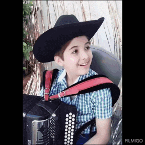 a young boy wearing a cowboy hat is playing an accordion