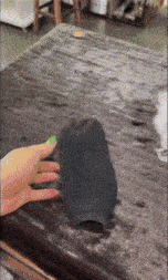 a person with green nails is holding a black object on a table