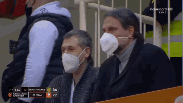 two men wearing face masks are watching a basketball game on nova sports hd