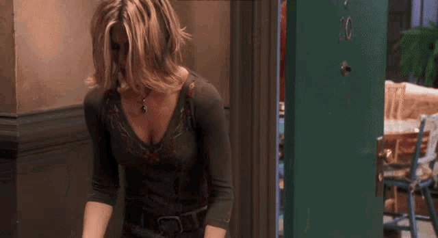 a woman in a grey shirt is standing in front of a green door .