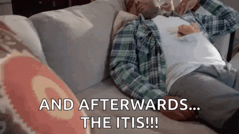 a man in a plaid shirt is laying on a couch with a cup of coffee in his hand .