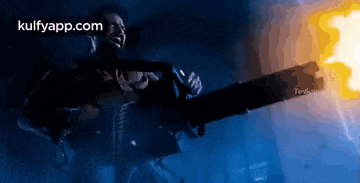 a man is holding a chainsaw with fire coming out of it in a dark room .