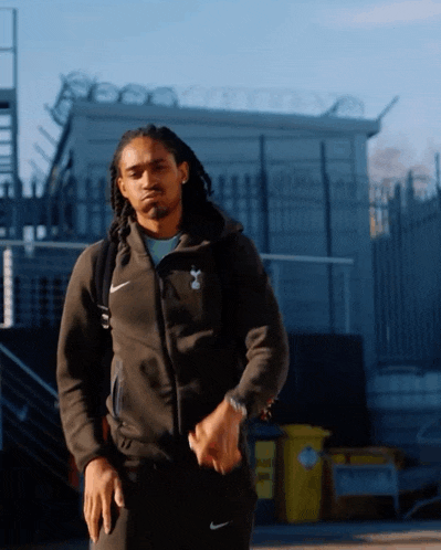a man wearing a nike jacket is walking down the street