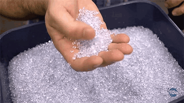 a person is holding a handful of clear plastic granules