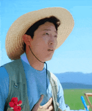 a man wearing a straw hat and a vest with a flower in his pocket
