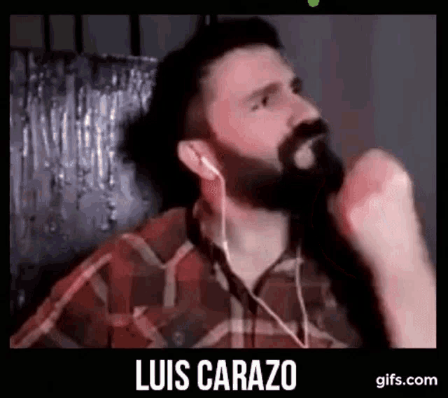 a man with a beard wearing headphones and a plaid shirt is making a funny face .