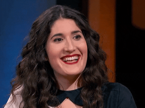 a woman with long curly hair and red lipstick is smiling