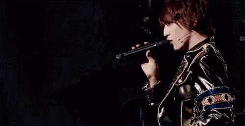 a man is singing into a microphone and making a peace sign with his hands .