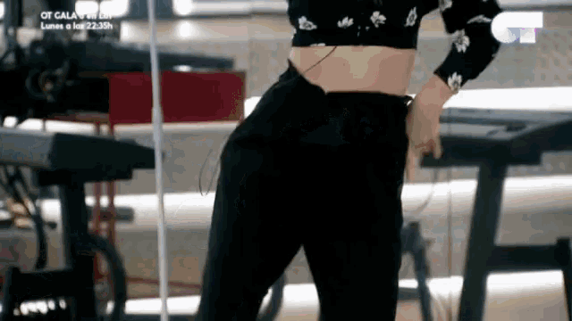 a woman in a crop top and black pants is standing in front of a keyboard .