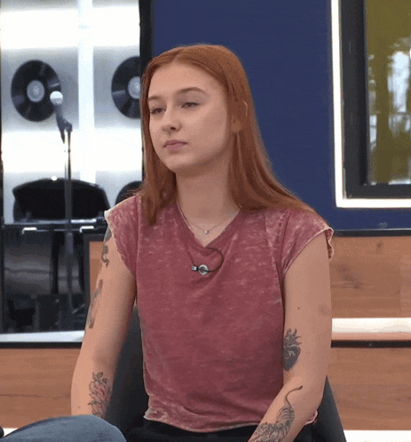 a woman with red hair and tattoos on her arms