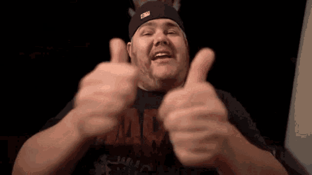 a man is giving two thumbs up in the dark .