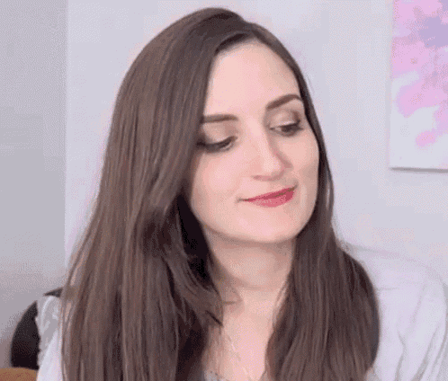 a woman with long brown hair and red lipstick is looking at the camera .