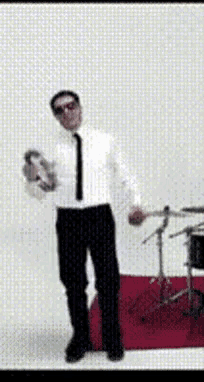 a man in a white shirt and tie is dancing in front of a drum set .