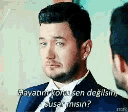 a man in a suit and tie is talking to another man in a foreign language .