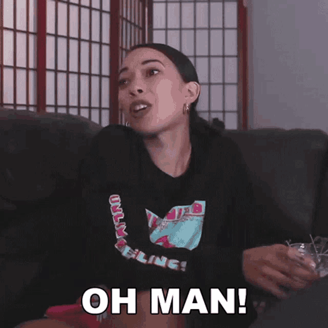 a woman is sitting on a couch and saying oh man !