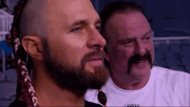 a man with a mohawk and a beard is standing next to another man .