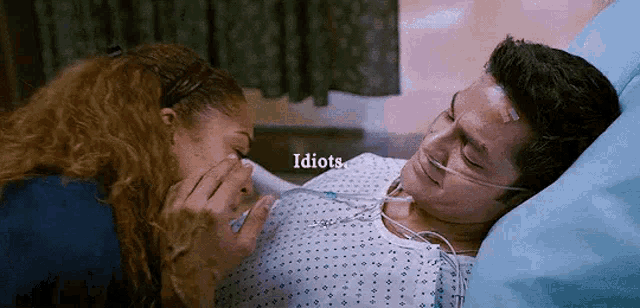 a woman is laying next to a man in a hospital bed with an oxygen mask .
