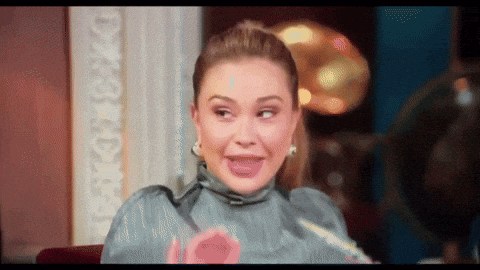 a woman is making a funny face while holding a pink object in her hand