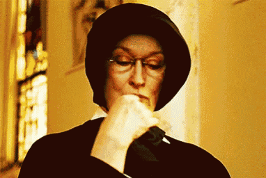 a woman wearing glasses and a hat is holding a knife in her mouth .