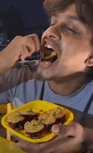 a man is eating a yellow plate of food with his mouth open