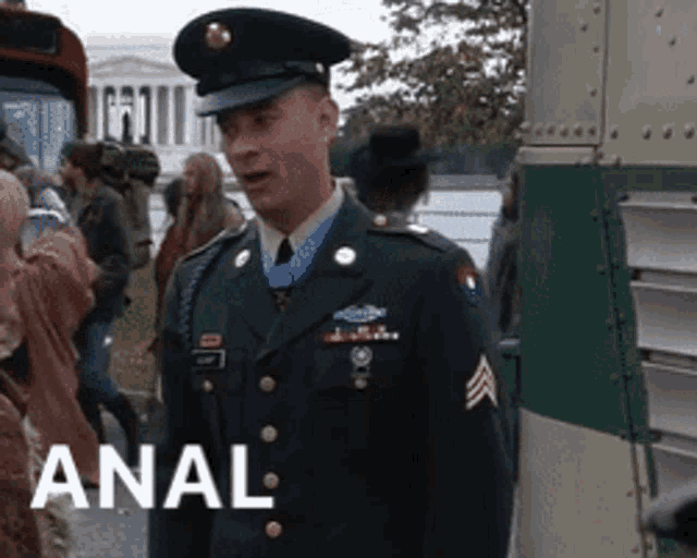 a man in a military uniform is standing in front of a bus with the word anal on the bottom