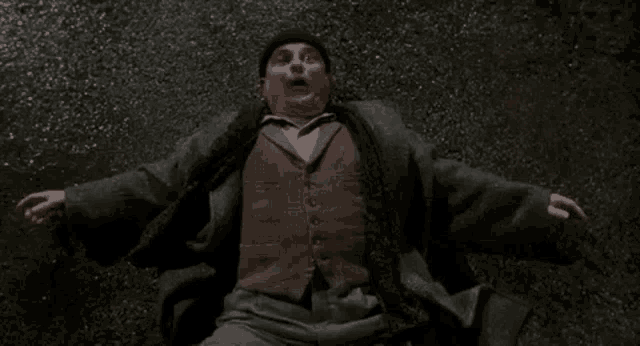 a man is laying on the ground with his arms outstretched and a surprised look on his face .
