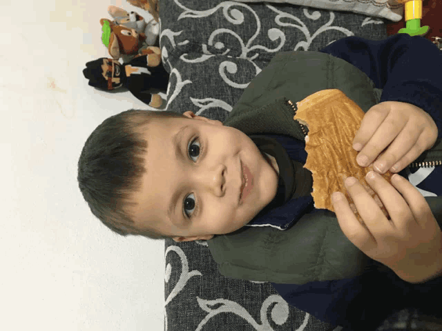 a young boy is holding a piece of food in his hands