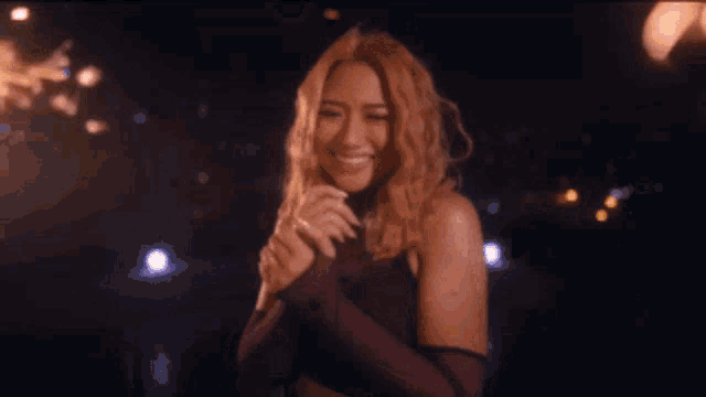 a woman in a purple dress is holding a sparkler in her hand