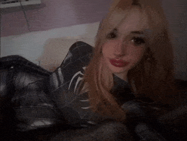 a woman in a black spiderman costume laying on a bed