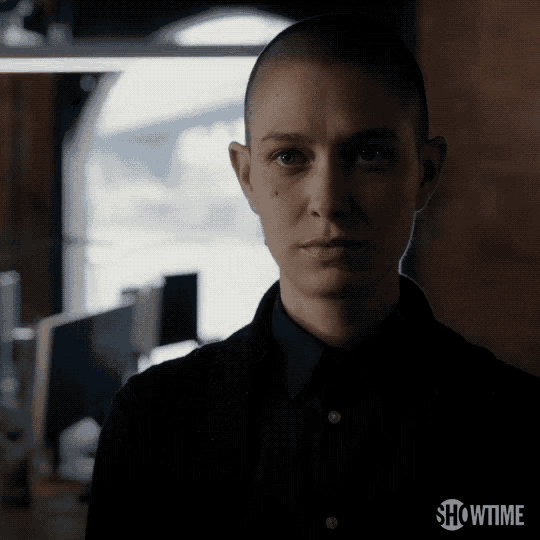 a woman with a shaved head is standing in a dark room with showtime written on the bottom
