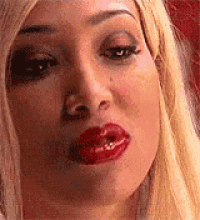a close up of a woman 's face with red lips making a face .