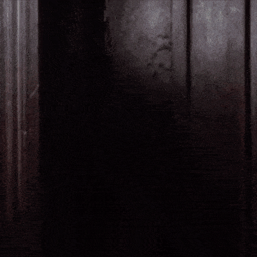 a woman is peeking out from behind a door while eating a piece of food .