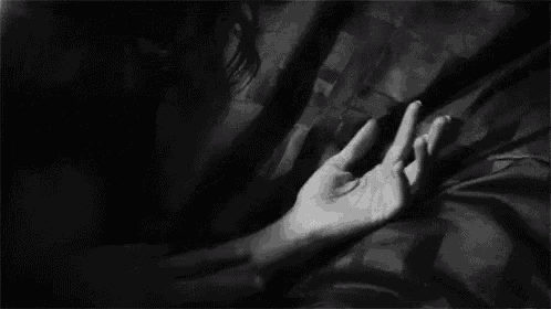 a black and white photo of a person holding another person 's hand on their chest .