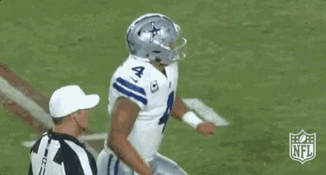 a football player wearing a white jersey with the number 4 on it is talking to a referee .