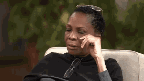 a woman is sitting in a chair with her eyes closed and the word lord written on the screen .