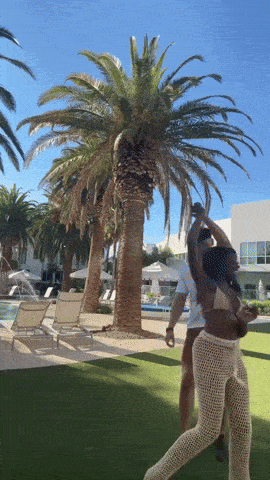 a couple dancing in front of palm trees