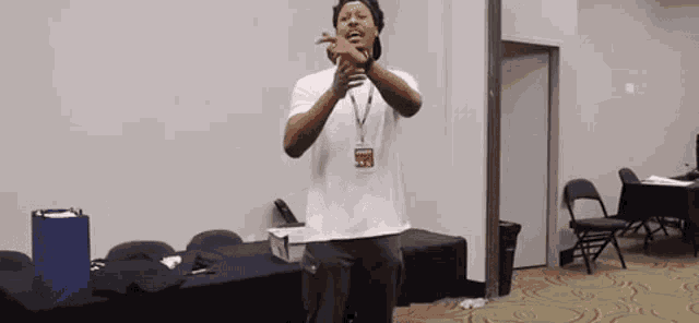 a man in a white shirt is standing in a room with a name tag around his neck .