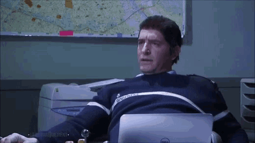 a man in a sweater with the word gendarmerie on it sits at a desk