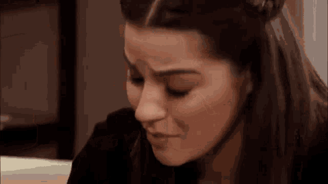 a woman is sitting at a table with her eyes closed and looking down .