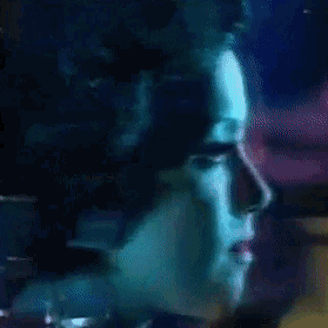 a close up of a woman 's face with a blue light behind her