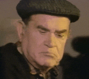 an older man wearing a hat and a black shirt looks at the camera