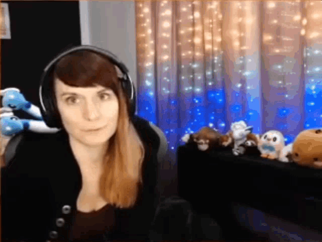 a woman wearing headphones is sitting in front of a table full of stuffed animals .