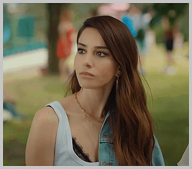 the woman is wearing a white tank top and a denim jacket .