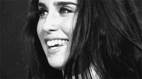 a black and white photo of a woman smiling with her mouth open .