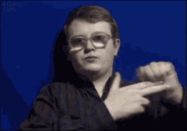 a young man wearing glasses is pointing at something with his finger