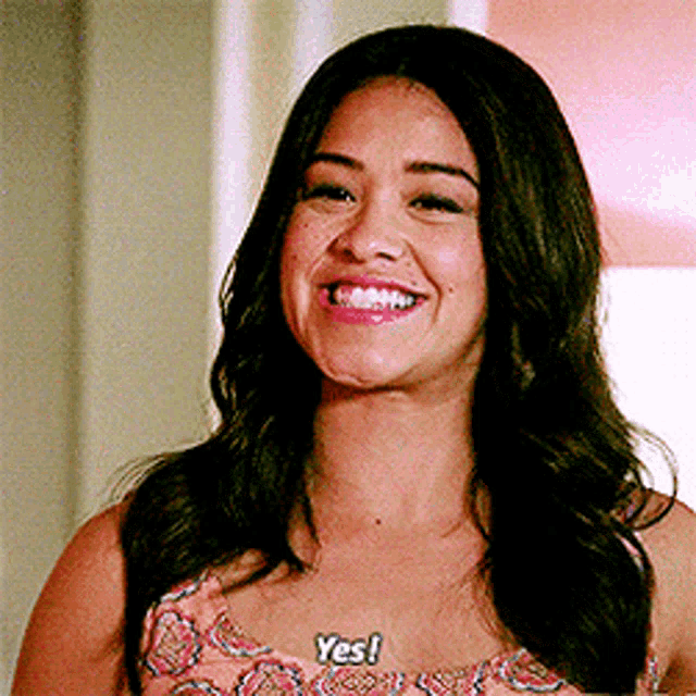 a woman wearing a necklace that says yes is smiling