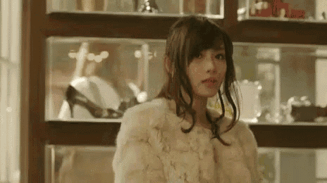 a woman wearing a fur coat is standing in front of a display case .