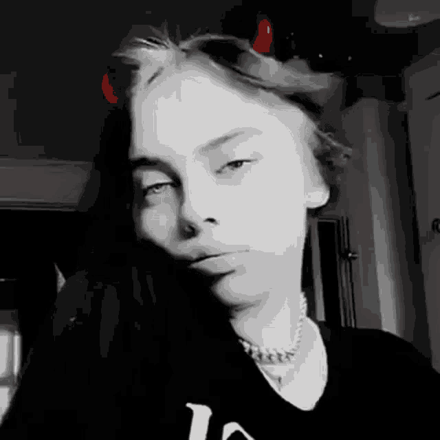 a black and white photo of a girl with horns on her head .