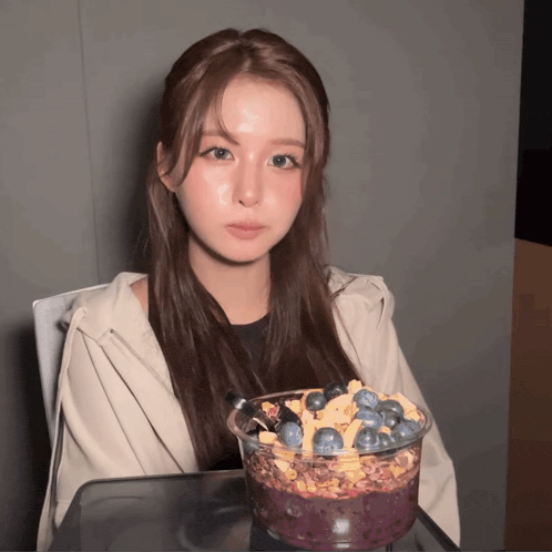 a woman sitting at a table with a bowl of blueberries