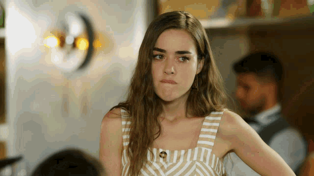 a woman wearing a striped tank top is making a face
